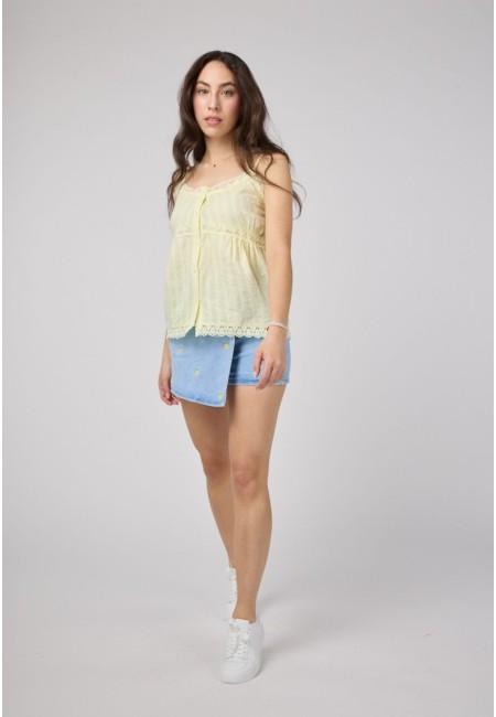 Parte delantera de una falda pantalón vaquera azul claro con bordado de limones, combinada con blusa amarilla.